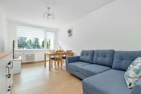 A bright open-plan bedroom combines a comfortable sofa and dining table in one spacious area. Large windows allow plenty of natural light to brighten the interior.
