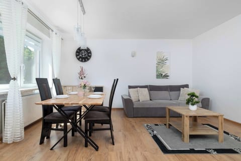 Bright living room with a dining table, sofa, coffee table, and large windows.