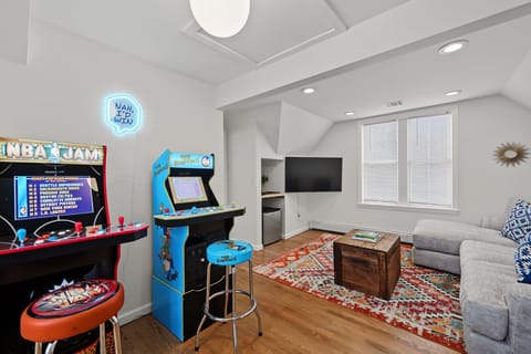 Tucked into a bright hallway with rich hardwood floors, this thoughtfully designed game station maximizes the home’s layout with compact arcade machines and a sleek refreshment station built right under the stairs.