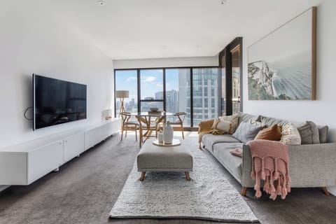 Sink into the plush sofa in the air-conditioned living area framed by floor-to-ceiling windows and skyline views, perfect for unwinding after city adventures.
