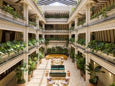 Lush greenery fills the atrium, where intricately carved columns rise around plush seating areas
