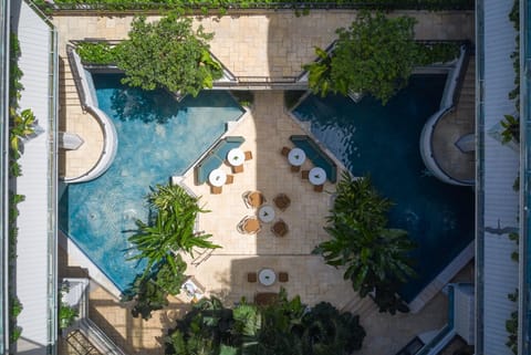 Aerial view of the tranquil pools nestled within greenery, with lounge chairs and tables arranged poolside