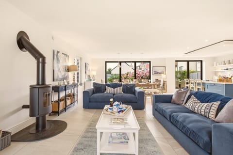 Open-plan lounge with wood burner, blue sofas and sliding doors to the garden