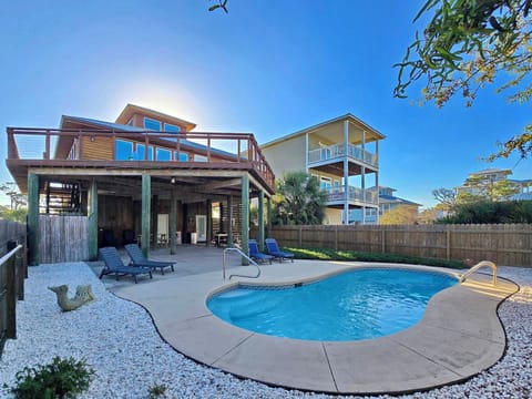 Modern coastal home with private pool, outdoor loungers, and covered patio perfect for relaxing under sunny skies.
