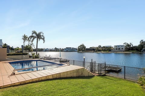 Watch sunlight move across the canal from the waterfront grounds, with the private pool in the foreground and Broadbeach’s skyline rising beyond the neighbouring homes.
