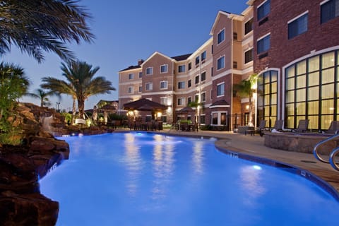 Illuminated outdoor pool with surrounding palm trees.