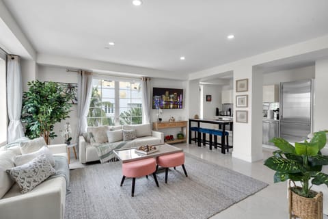 Bright, open-concept living space designed for relaxing in style — plush seating, a chic bar nook, and a fully equipped kitchen flow together seamlessly, all filled with natural light just moments from the beach.