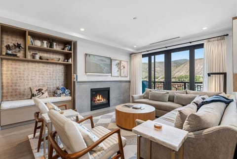 Open-concept living space featuring a cozy gas fireplace, comfortable seating, smart TV and walkout balcony with a view of the bustling heart of the Eagle River Valley
