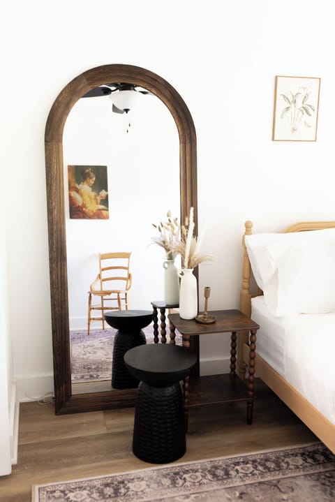 Bright bedroom with arched mirror, cozy styling, and elegant decor