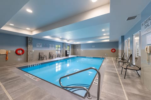 Indoor heated pool with accessible steps, handrails, and pool safety signage.