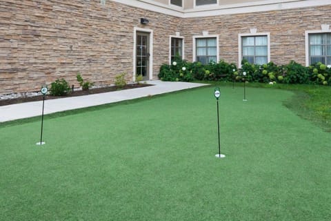 Outdoor putting green with flag holes adjacent to the building.