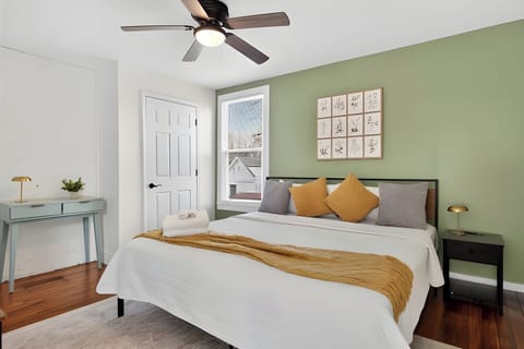 Rest easy in this bright bedroom with a comfy white bed and a cheerful green accent wall. The yellow blanket adds a perfect pop of sunshine to the space.