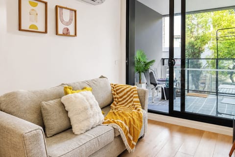 Bright cozy lounge with private balcony and leafy outdoor views