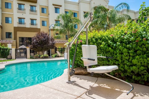 Accessible outdoor pool with pool lift and lounge chairs.