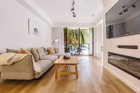 A light-filled living area invites slow mornings and cosy evenings with an L-shaped sofa, TV, and split-system air conditioning and heating.