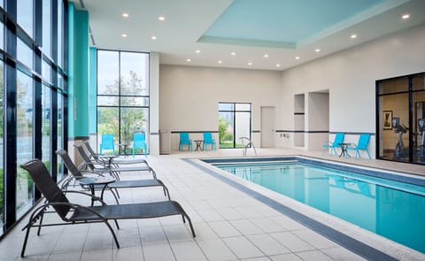 Pool deck with lounge chairs and large windows.