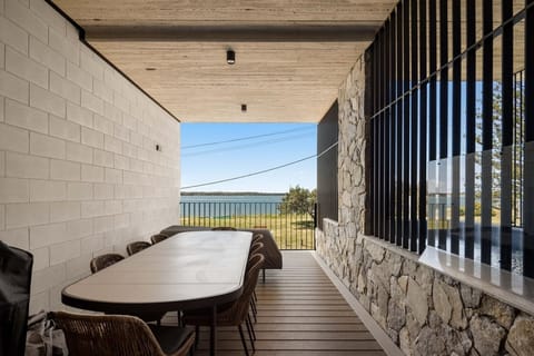 Covered terrace on the broadwater, table set for eight, water the length of it