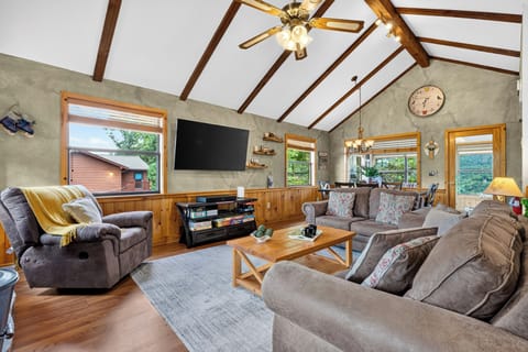 Open-concept living room with vaulted wood ceilings, stone fireplace, and comfortable sofas.