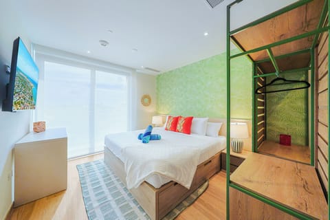 Unwind in your tropical-inspired bedroom with lush botanical wallpaper, crisp linens, and a spacious open concept wardrobe waiting for your belongings.