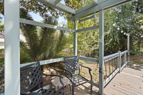 Relax under the shaded pergola and take in the lush greenery from a quiet deck seat, string lights ready for easy evenings.