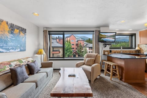 Relax in your spacious living area where natural light fills the room and windows frame stunning mountain vistas. The open layout connects you to a fully equipped kitchen, perfect for preparing meals after a day of adventure.