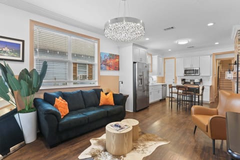 Spacious living area filled with natural light, featuring comfortable seating, vibrant décor, and an open layout connecting the living, dining, and kitchen spaces.