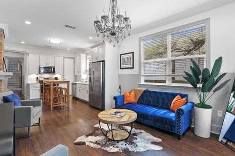 Spacious open-concept living area with comfortable seating, vibrant artwork, natural light, and easy flow into the dining area and kitchen.