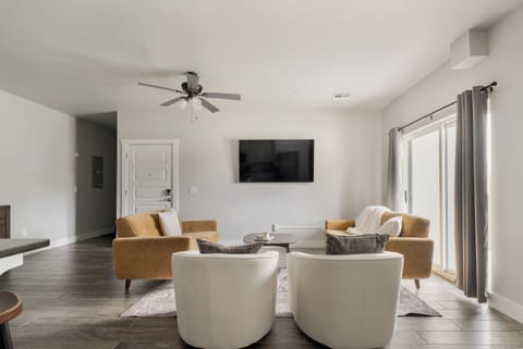 Bright modern living room with TV, cozy seating, and natural light