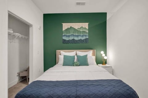Cozy bedroom with green accent wall, stylish decor, and open closet