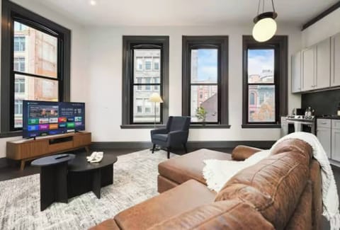 Bright loft-style living room with big windows, city views, and smart TV