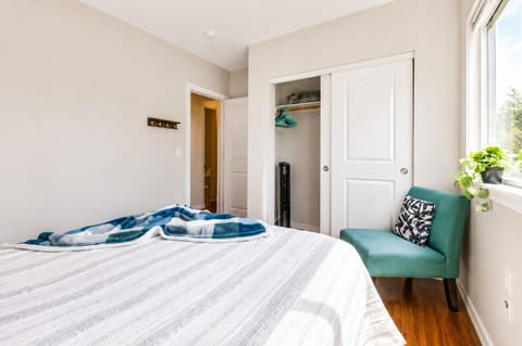Bright, cozy bedroom with natural light, closet space, and stylish seating