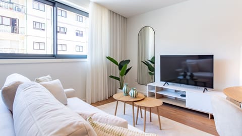 Relax in the bright living area, featuring a comfortable sofa and a large TV for entertainment, perfect for unwinding after a day of sightseeing. Abundant natural light streams through the window, making the space feel open and inviting for your comfort. 