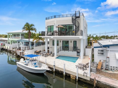 Aerial waterfront view of Mar de Cielo with its pool, patio, dock, and canal frontage.