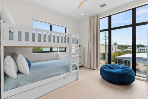 Bright bunk room with two stacked full-size bunks, large windows, and a blue beanbag chair.