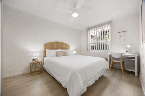Wake refreshed in the bedroom, where a queen bed, dedicated workspace and calming coastal styling create a comfortable retreat for both rest and productivity.
