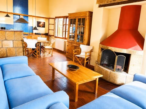 A cosy living room centred around a traditional fireplace, with comfortable blue sofas, a wooden coffee table and warm natural finishes. It is an inviting place to sit back, talk, read or simply enjoy a quiet evening indoors