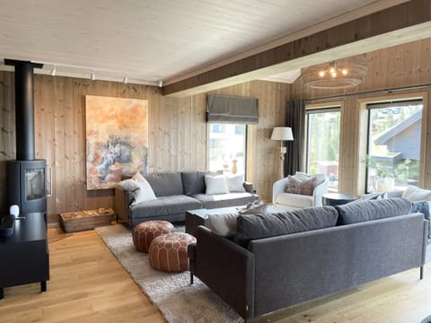 Cozy living room filled with natural light and large windows offering beautiful views of the surrounding landscape, creating a warm and inviting cabin atmosphere.