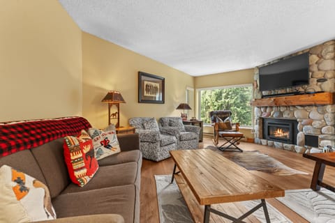 Settle into this warm living space where a crackling stone fireplace and rustic wood furnishings invite you to unwind after exploring the outdoors.