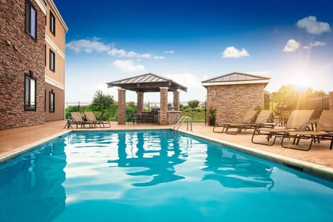 Outdoor pool area with lounge chairs and a covered seating space.