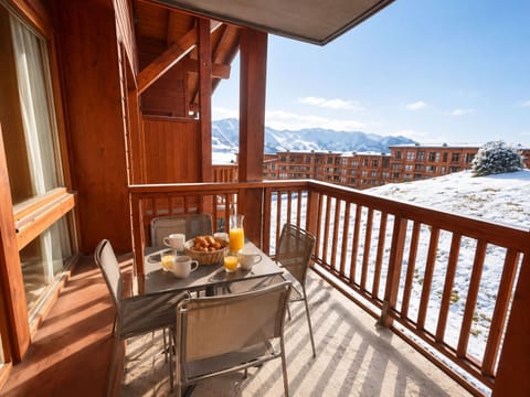 Private balcony with table and chairs overlooking snow-covered peaks