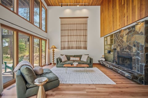 Settle into this sun-drenched living room with vaulted wood ceilings, plush sage sofas, and a striking stone fireplace—your cozy retreat after a day exploring the outdoors.