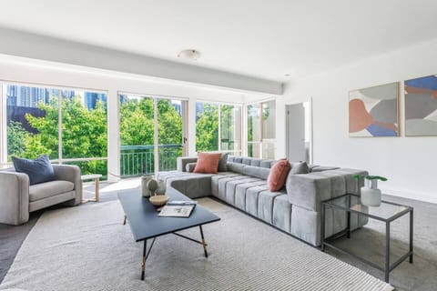 Leafy treetop views and soft natural light create a calm backdrop for the living area.