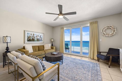 Living room with sofa seating, accent chairs, a ceiling fan, and direct Gulf views from the balcony doors.