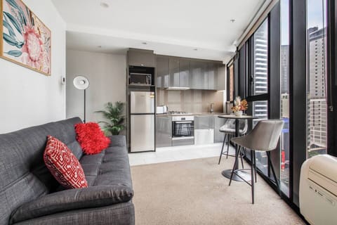 Relax in the light-filled living area featuring a two-seater sofa and vibrant details. Though compact, the space is thoughtfully styled for comfort and function.