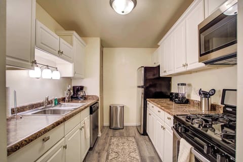 Fully equipped galley kitchen featuring sleek appliances, white cabinetry, ample counter space, and warm lighting—perfect for cooking and dining in comfort.