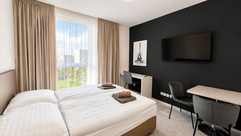 Bright modern twin room with large window, desk, and flat-screen TV