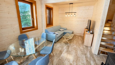 Bright wood-clad lounge with dining area, TV, and cozy cabin charm