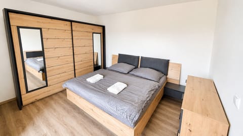 Modern wood-accent bedroom with mirrored wardrobe and cozy king bed