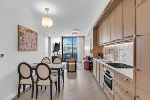 Elegant in-unit dining area with designer chairs, warm wood cabinetry and stylish pendant lighting — perfect for intimate meals at home