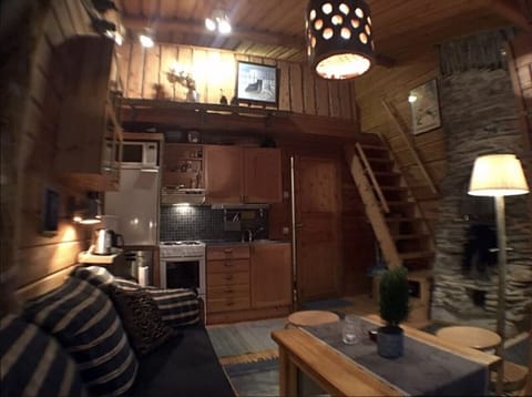 Open-plan living area and kitchen with wooden stairs leading up to the loft.